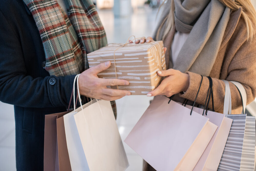 midsection of young casual couple holding paperbag ZA7HU52