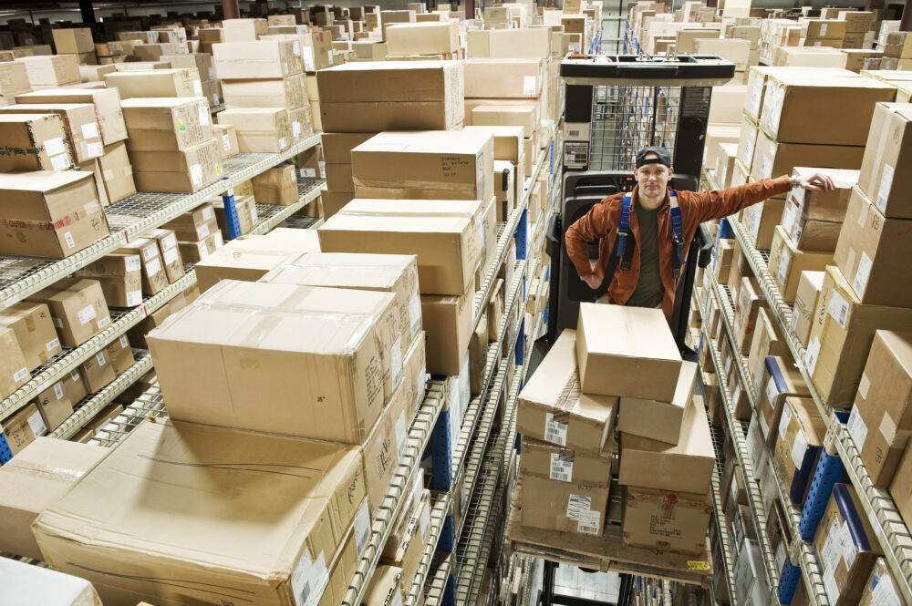 a warehouse worker standing on a motorized stock p WWS7KFK